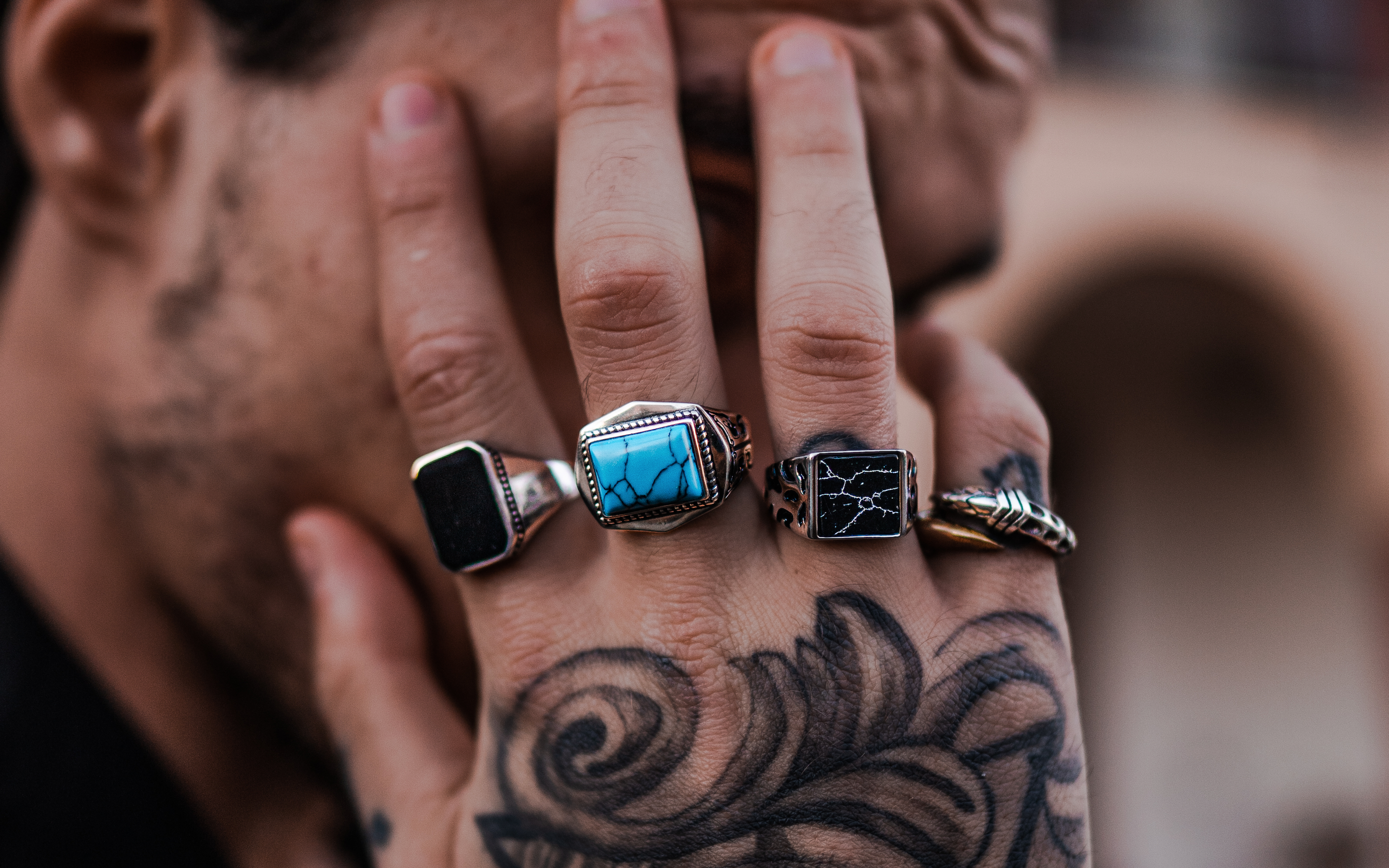 A man with tattoos and rings on his hands.