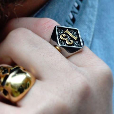 A silver and gold Lucky 13 Gold Skull Ring with the number 13 on it, from Rebel Saint Co.
